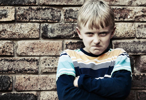 istock Angry boy glares at the camera with arms folded 973180786