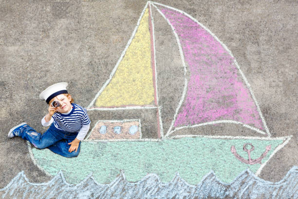 Little girl drawing with crayons on a paper roll sticked on a wall