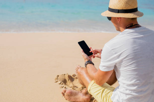istock Man with phone on the beach 973181428