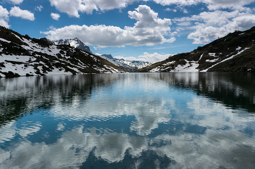 A gorgeous mountain lake in the Alps with reflections and snow remnants