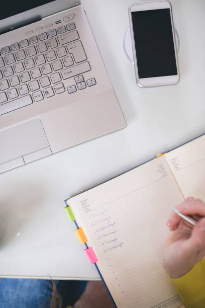 istock Close up of female hands with laptop computer, notebook and pen taking notes in business office 973181522