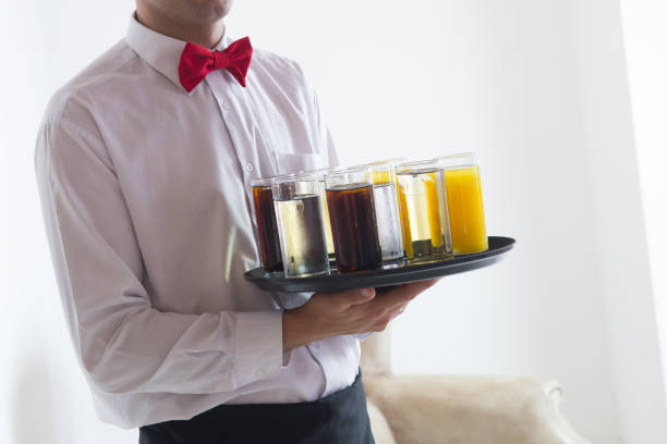 istock Waiter With Red Bow Standing With Champagne Glasses And Strawberries 973184328