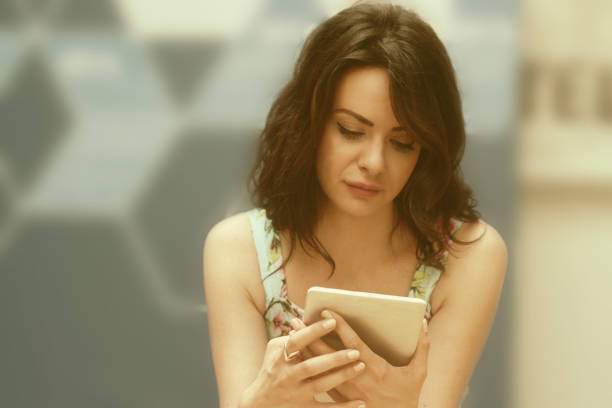 istock Young woman sitting and using phone 973194144