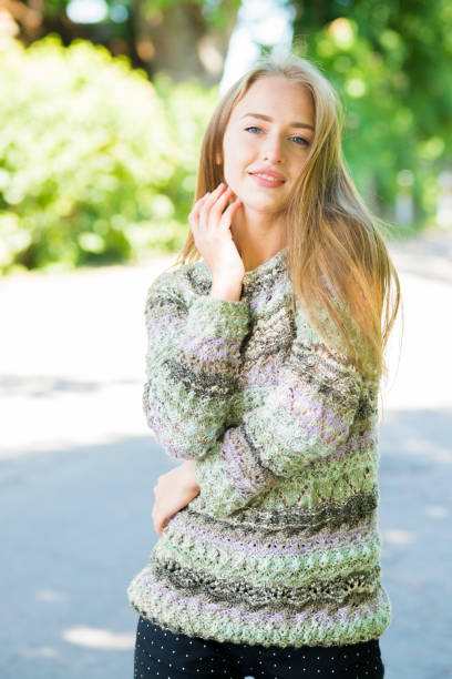 istock The blonde with blue eyes, in a knitted pullover, poses outdoors 973194504