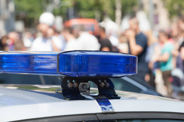 istock Police car flashing lights in focus, blurred people in background 973210178