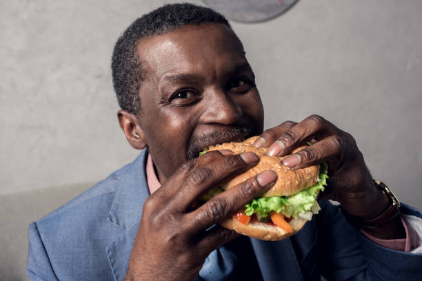 istock hungry african american man eating hamburger 973212536