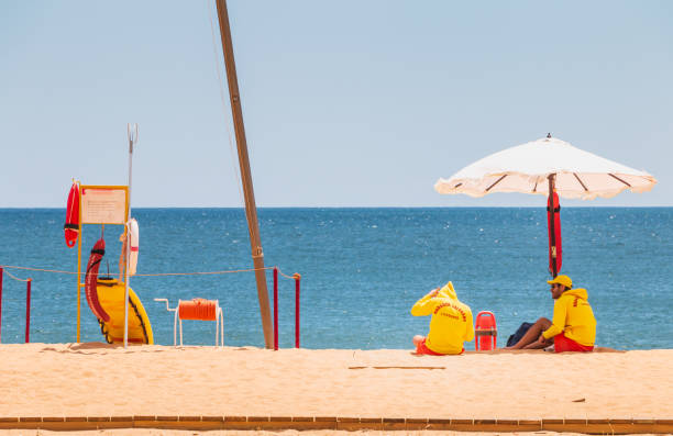 rettungsschwimmer bekleidet mit gelben sitzen auf einem stuhl am strand - lifeguard orange nature beach stock-fotos und bilder