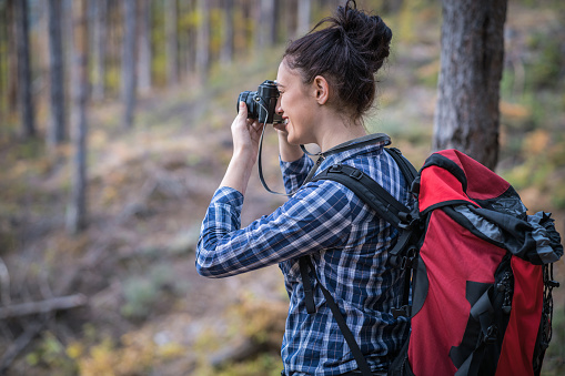 Young female photographer trekking in the mountains and making pictures