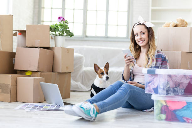 istock Young woman unpacking in new home, dog 973261532