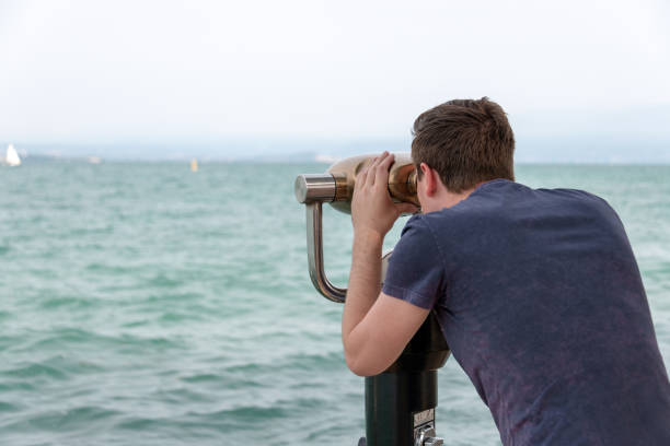 istock Young man uses a telescope looking over Lake Garda, Italy 973262014
