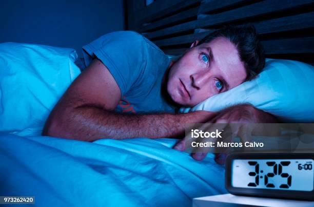 Restless Worried Young Attractive Man Awake At Night Lying On Bed Sleepless With Eyes Wide Opened Suffering Insomnia Sleeping Disorder Depressed And Sad In Rest Privation Stress Concept Stock Photo - Download Image Now