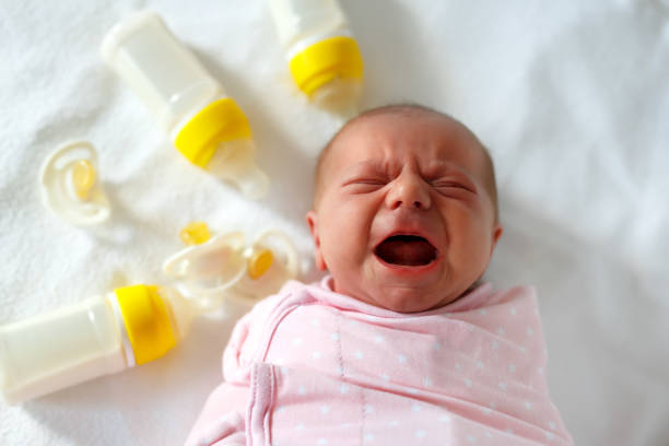 ボトルを看護と新生児の女の子が泣いています。赤ちゃんの数式を飲む。 - female nurse 写真 ストックフォトと画像