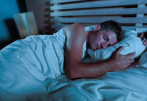 istock young attractive and handsome tired man on his 30s or 40s in bed sleeping peacefully and relaxed at apartment bedroom resting comfortable in night lifestyle concept on dark studio light 973265614