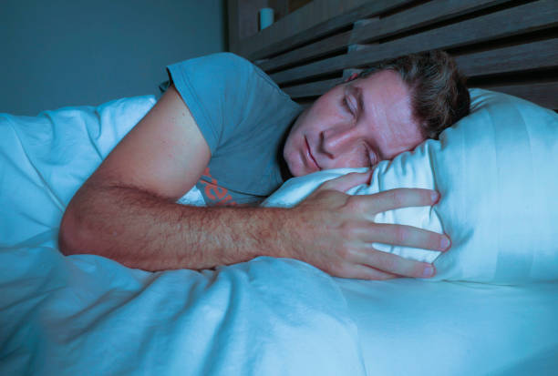 istock young attractive and handsome tired man on his 30s or 40s in bed sleeping peacefully and relaxed at apartment bedroom resting comfortable in night lifestyle concept on dark studio light 973265646