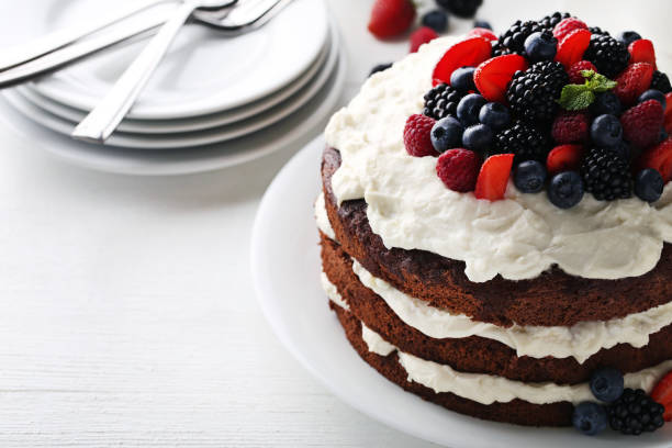 istock Delicious chocolate biscuit cake with berries on white wooden table 973270944