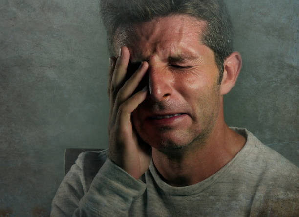 istock young sad and desperate Caucasian man crying feeling lost and suffering stress and depression crying alone isolated on grunge background in dramatic face expression and emotions concept 973274778