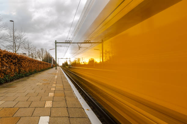trein van de nederlandse spoorwegen passeert het platform van een treinstation in delft op hoge snelheid - trein nederland stockfoto's en -beelden
