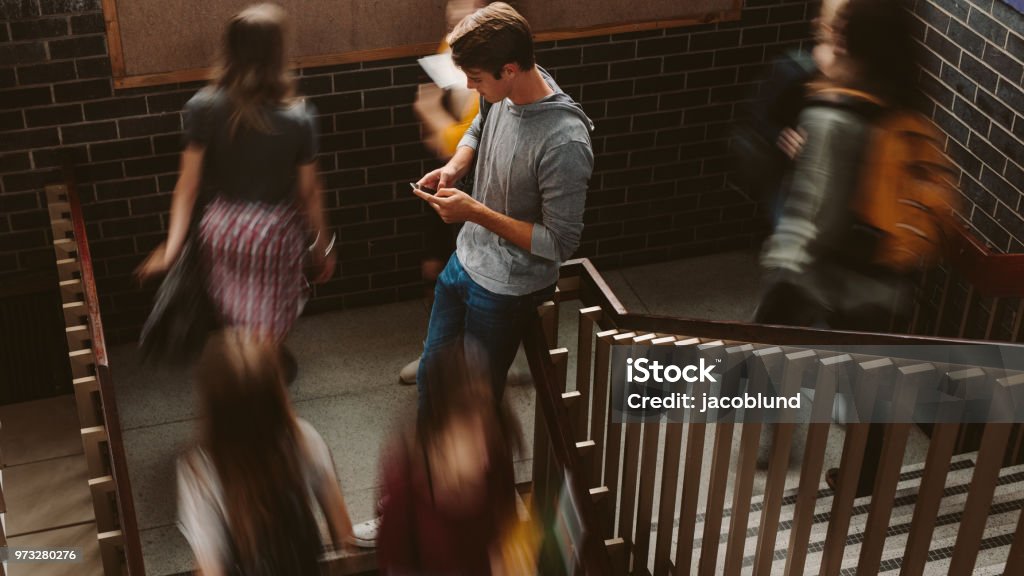 Students on steps of college campus Young man standing on the staircase in college with girls walking by. Students on steps of college campus. Telephone Stock Photo