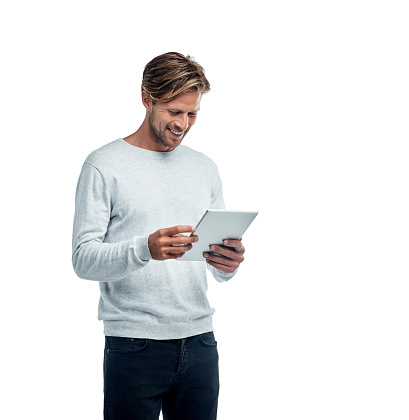 Studio shot of a handsome young man using his tablet while standing against a white background