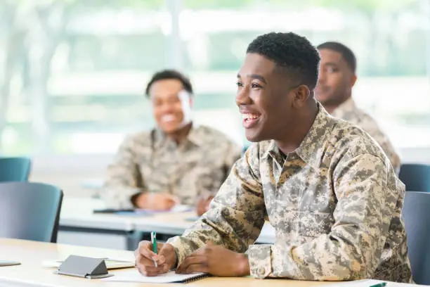 African American male cadet smiles while listening to professor in military academy.