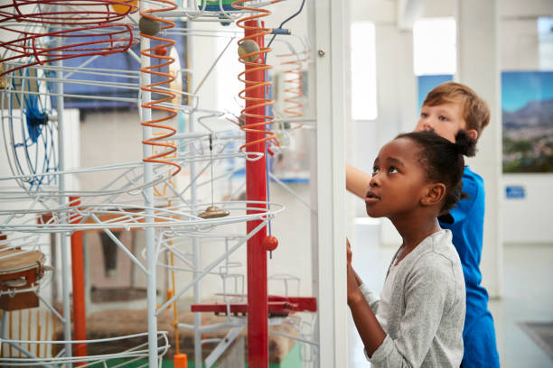 istock Two kids looking at a science exhibit, waist up 973292224