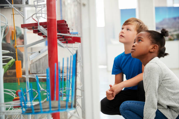 istock Two kids kneeling and looking at a science exhibit 973292336