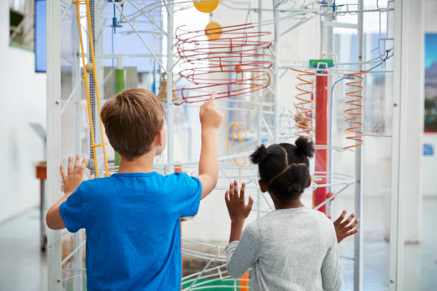 Two kids looking at a science exhibit,  back view Two kids looking at a science exhibit,  back view museum stock pictures, royalty-free photos & images