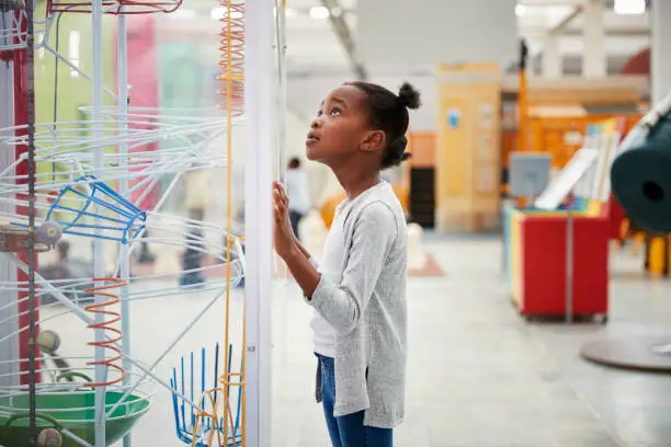 Photo of Young black girl looking at a science exhibit, close up