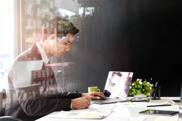 istock Asian handsome young businessman working on a pc and paper works. 973297004