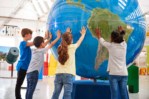 Group of school kids holding giant globe at a science centre