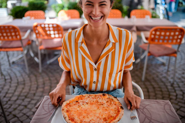 счастливая женщина ест пиццу. - multi colored fashion horizontal summer стоковые фото и изображения