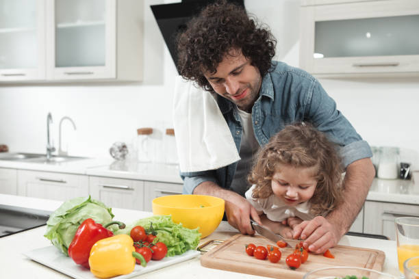 istock Curious daughter is looking how her dad preparing lunch 973300602