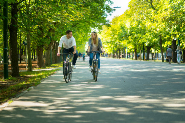 sightseeing couple on bicycles in urban park - prater park imagens e fotografias de stock