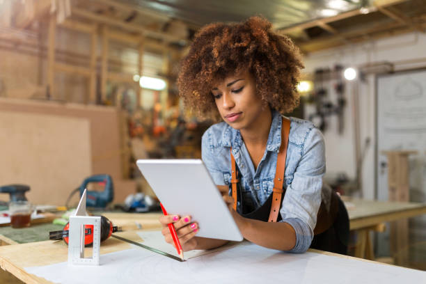 young woman using a tablet in her workshop - carpenter carpentry craft skill imagens e fotografias de stock