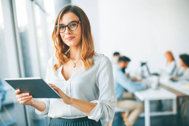 istock Elegant businesswoman standing in office with digital tablet 973304864