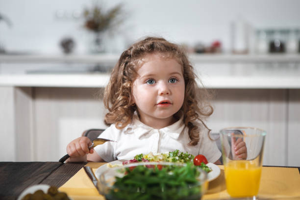 istock Pretty kid eating healthy vegetables at home 973306146