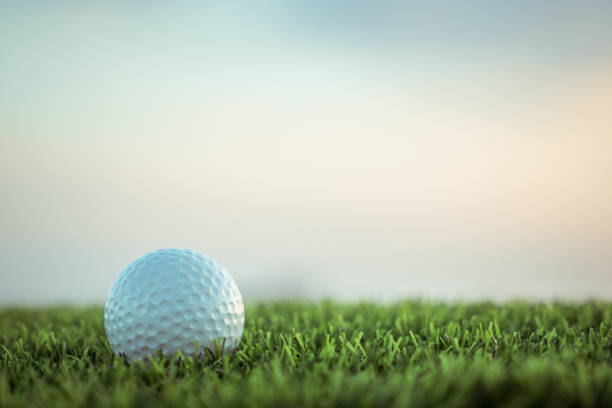 istock Golf ball on grass on sky background 973310792