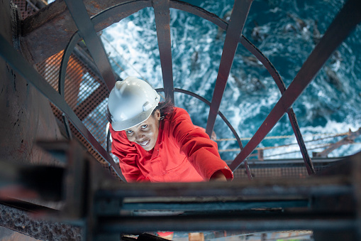 Mossel Bay, Southern Cape, South Africa, December 13,  2007.  A woman roughneck oil drilling worker climbs on the rig, FA Platform,  off the cost of Mossel Bay.