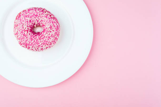 istock Pink glazed donut on pink pastel background 973319592