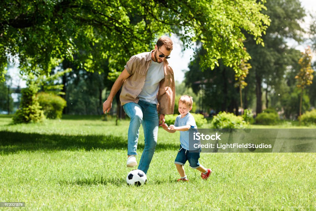 dad and son playing football at park Family Stock Photo