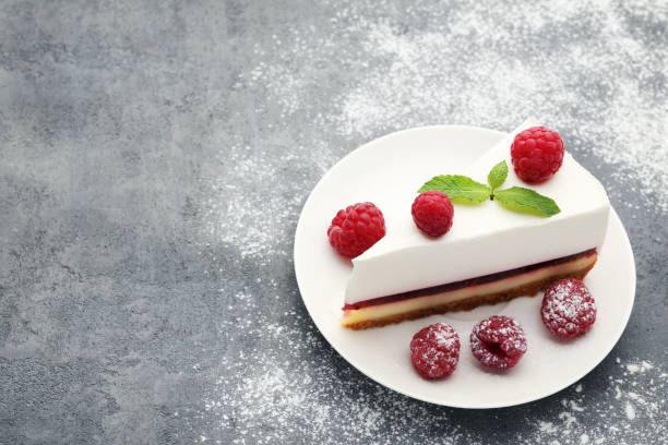 istock Tasty raspberry cheesecake in plate on grey wooden table 973330434