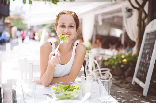 Happy woman on vegetarian diet eating salad for lunch
