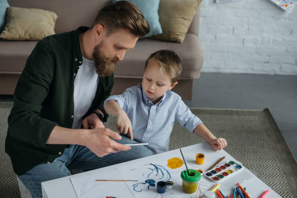 istock father and little son using smartphone together at home 973333064