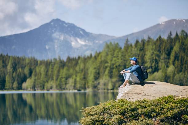 istock Tourist resting on rock above lake 973334956