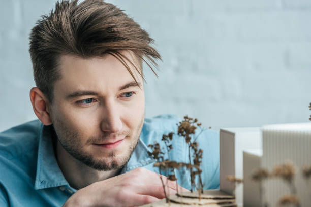 istock selective focus of architect looking at self made building model in office 973337374