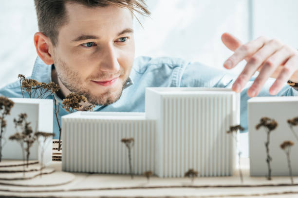 istock selective focus of smiling architect looking at self made building model in office 973338778