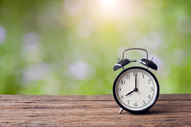 istock 8 o'clock retro clock on wooden table 973343950
