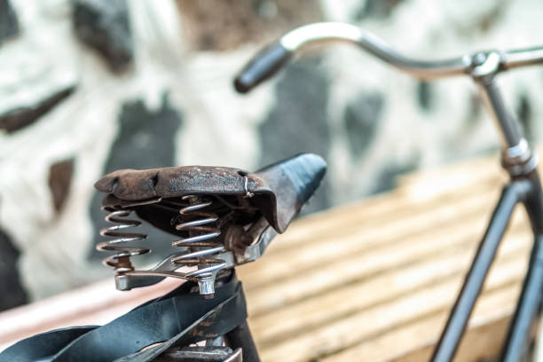 An old bicycle seat with a spring shock absorber. Vintage bicycle on the stone wall background.