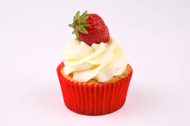 Red cupcake with white cream decorated with strawberry on white background. Picture for a menu or a confectionery catalog.
