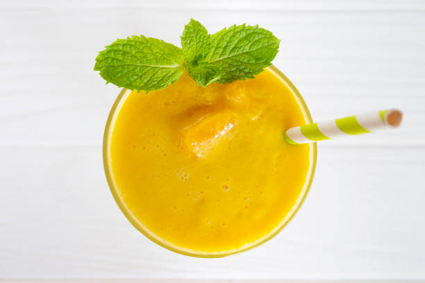 istock Mango smoothies juice and fruit mango yellow on white wood from the top view. 973363530